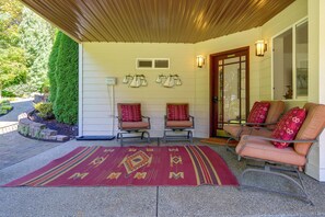 A covered porch with two chairs and a sofa, a patterned rug, and sailboat decorations on the wall. - Snohomish Executive Suite w/ Deck & Fire Pit (Snohomish)