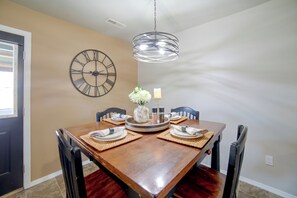 Ein Esszimmer mit Holztisch, vier Stühlen, einer Wanduhr und einer Hängeleuchte.