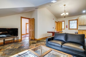 A living room with a television, a black leather sofa, and a glass coffee table. - Retreat 7 Mi to Northstar Skiing! Easy I-80 Access (Truckee)