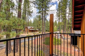 A wooden cabin surrounded by tall pine trees, with a paved road in the background. - Retreat 7 Mi to Northstar Skiing! Easy I-80 Access (Truckee)
