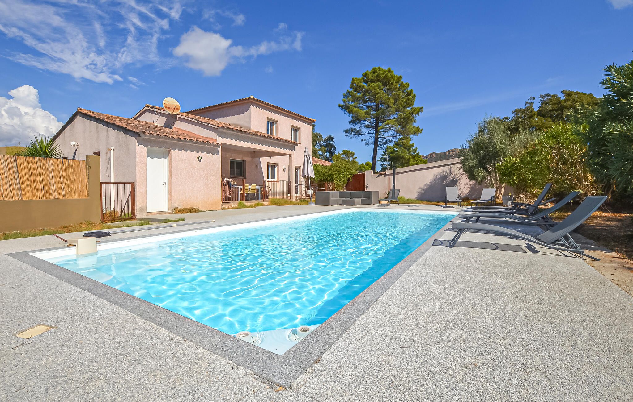 A swimming pool with lounge chairs and a building with a tiled roof.