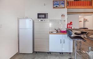 A compact kitchen with a refrigerator, microwave, and a sink with a modern faucet. - Beautiful apartment in Folelli with WiFi (Folelli)