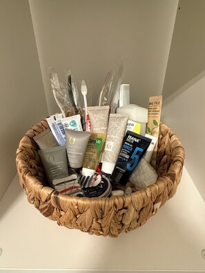 A basket containing various toiletries including shampoo, conditioner, body wash, and a comb. - New & cozy in the heart of the city (Hamburg)
