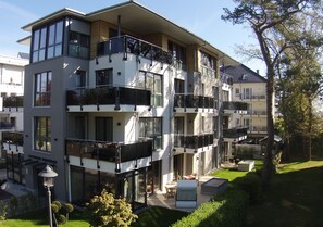 Een meerlaags woongebouw met balkons, een klein terras en een verzorgd gazon.