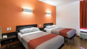 A hotel room with two beds, a nightstand, a heater, and a window with curtains.