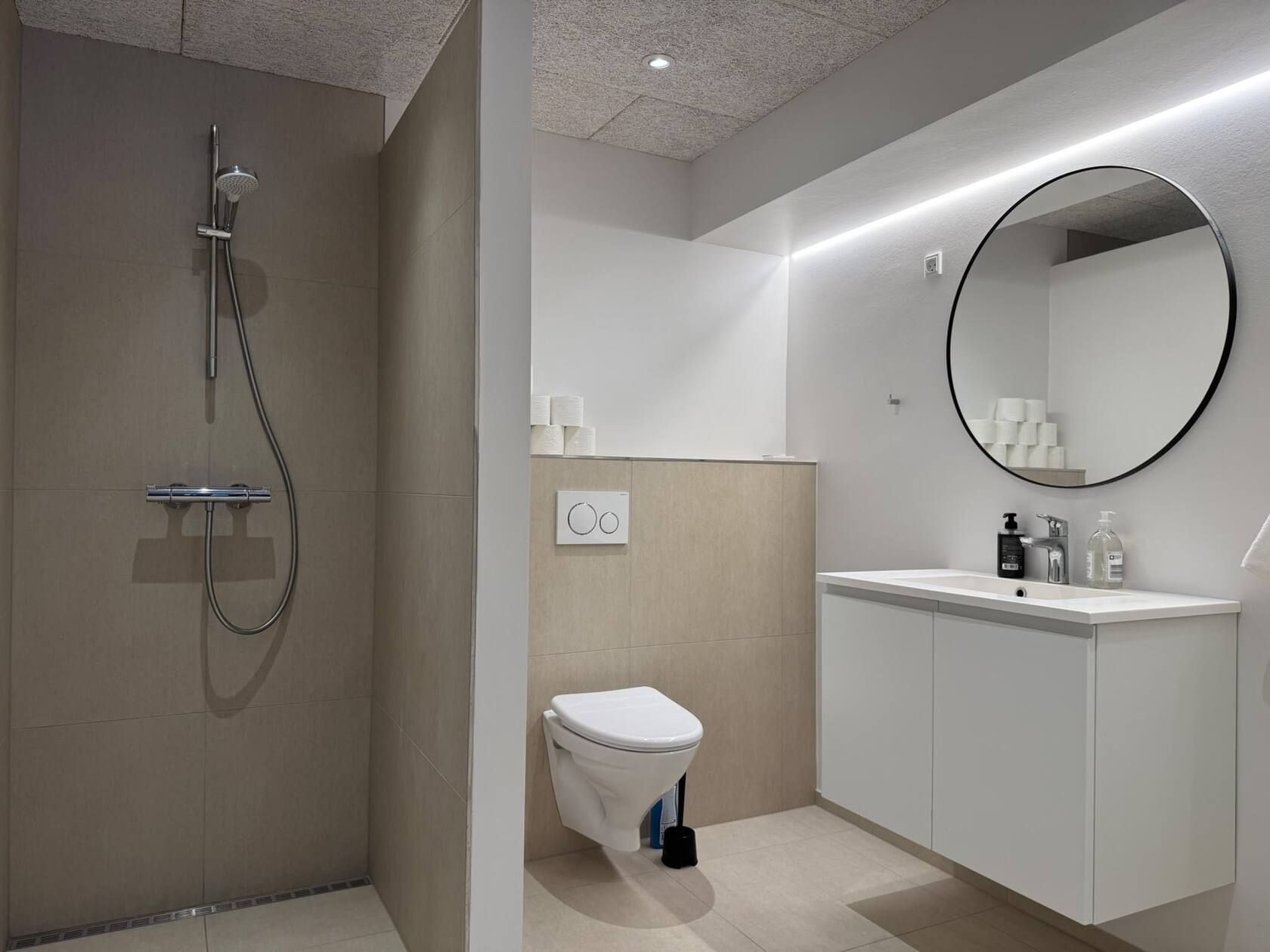 A modern bathroom with a shower, toilet, and sink.