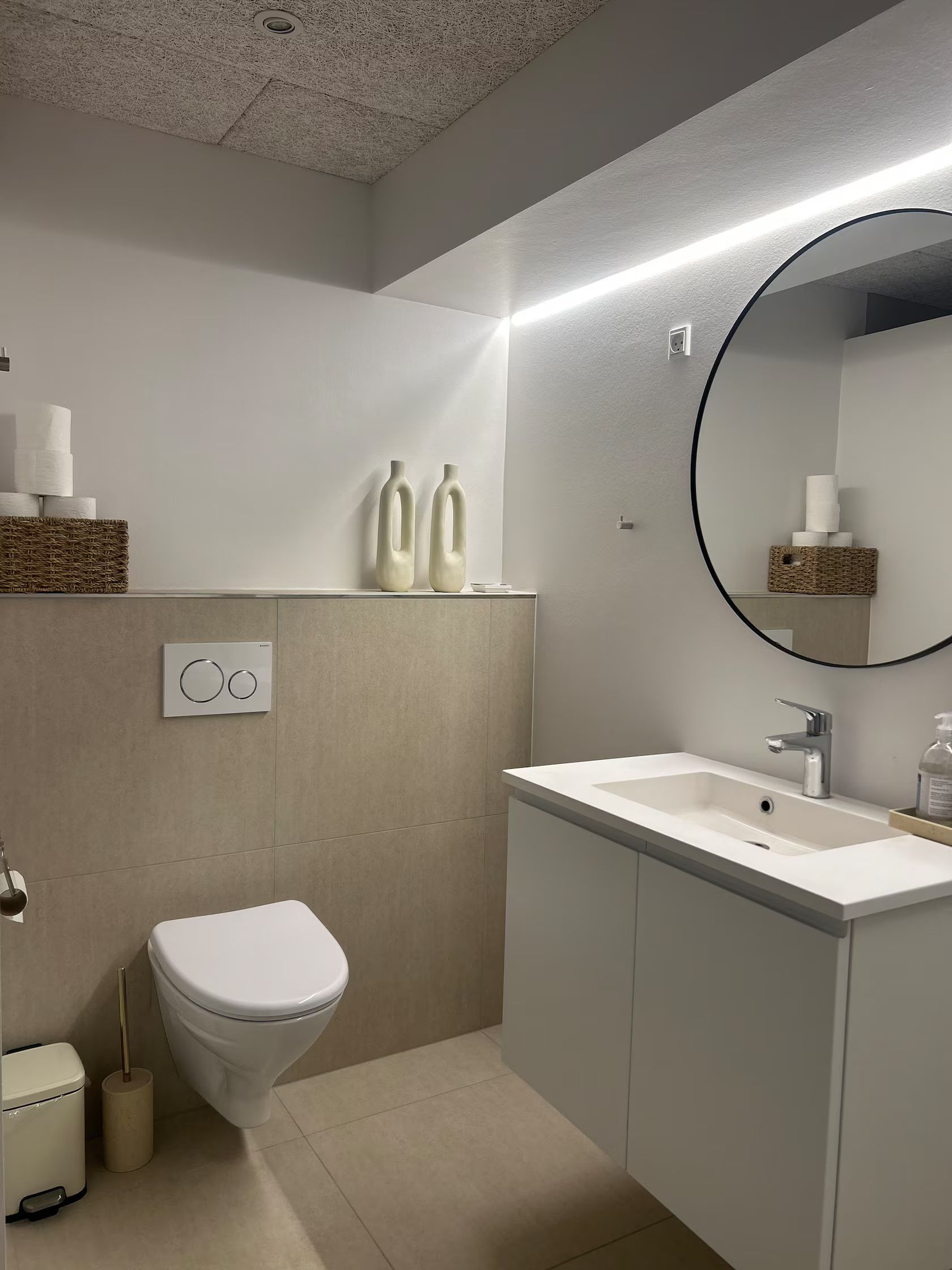 A modern bathroom with a toilet, sink, and mirror.