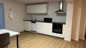 Una cocina moderna con armarios blancos, una campana extractora de acero inoxidable, un microondas y un horno.