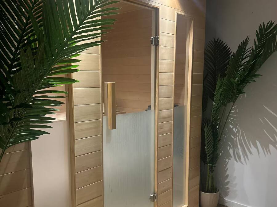 A modern bathroom with a wooden vanity, a glass shower enclosure, and potted plants.