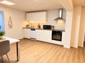 A modern kitchen with white cabinetry, a built-in dishwasher, a microwave, and an oven.