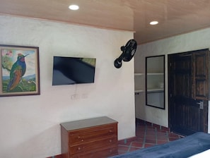 Una habitación con televisión montada en la pared, un aparador de madera y una puerta.