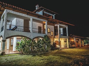 A two-story building with a balcony on the upper floor, a covered patio area, and a well-maintained lawn. - Hotel Casona Montañesa Quindío (Montenegro)