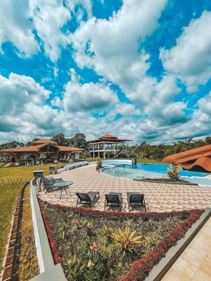 Un resort con piscina, mobiliario exterior y un pabellón cubierto.