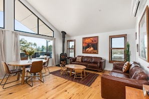 Ein geräumiges Wohnzimmer mit einem Holzesstisch, Ledersofas und einem Kamin.