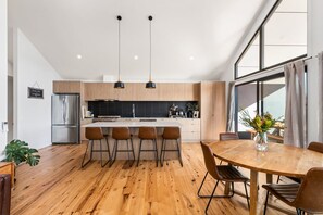 A modern kitchen with a central island, bar stools, and pendant lighting. - Heysen Alpine House (Jindabyne)
