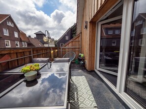 A balcony with a glass door, a table with a plant, and a chair. - Resin Passion Braunlage (Braunlage)
