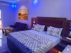 Un dormitorio con una cama grande, un sofá, una mesita y un cuadro en la pared.