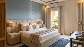 Une chambre d’hôtel avec un grand lit, des tables de chevet, un bureau et un ventilateur de plafond.