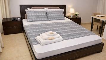 A hotel room with a large bed, two bedside tables, a desk, and a chair.