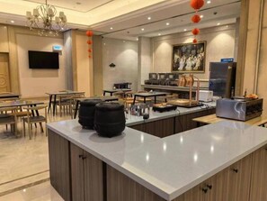 A hotel lobby with a reception desk, seating area, and a television mounted on the wall. - Vienna Hotel (Chongqing)