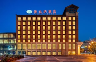 Un edificio de hotel de varios pisos con ventanas iluminadas y un cartel llamativo en la parte superior.