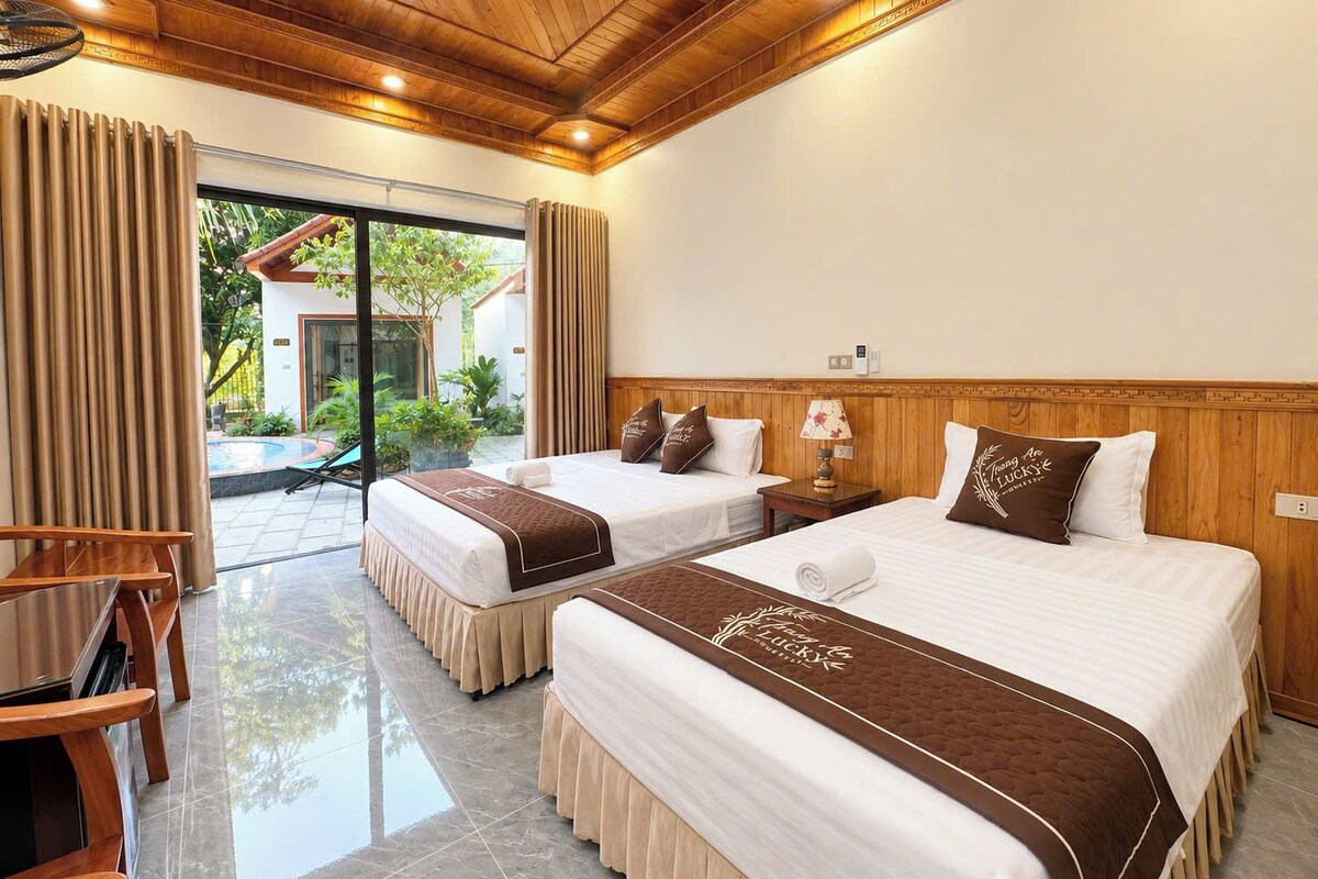 Een hotelkamer met twee bedden, een houten plafond, uitzicht op de omgeving en een klein tafeltje.