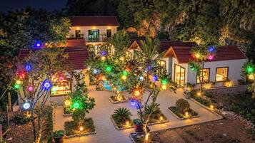 Een hotel bestaande uit meerdere gebouwen, met een geplaveid binnenterrein en bomen versierd met kleurrijke lichtjes.