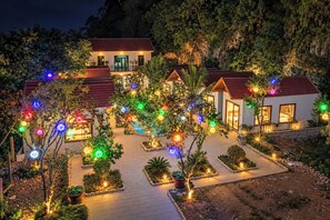 Een hotel bestaande uit meerdere gebouwen, met een geplaveid binnenterrein en bomen versierd met kleurrijke lichtjes.