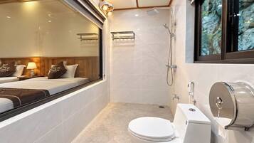 Een moderne badkamer met toilet, douche en een raam met uitzicht op een rotsachtig landschap.
