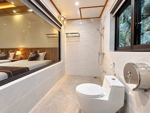 Een moderne badkamer met toilet, douche en een raam met uitzicht op een rotsachtig landschap.