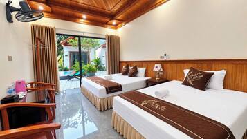 A hotel room with two beds, a wooden ceiling, a view of a pool, and a small table with a lamp.