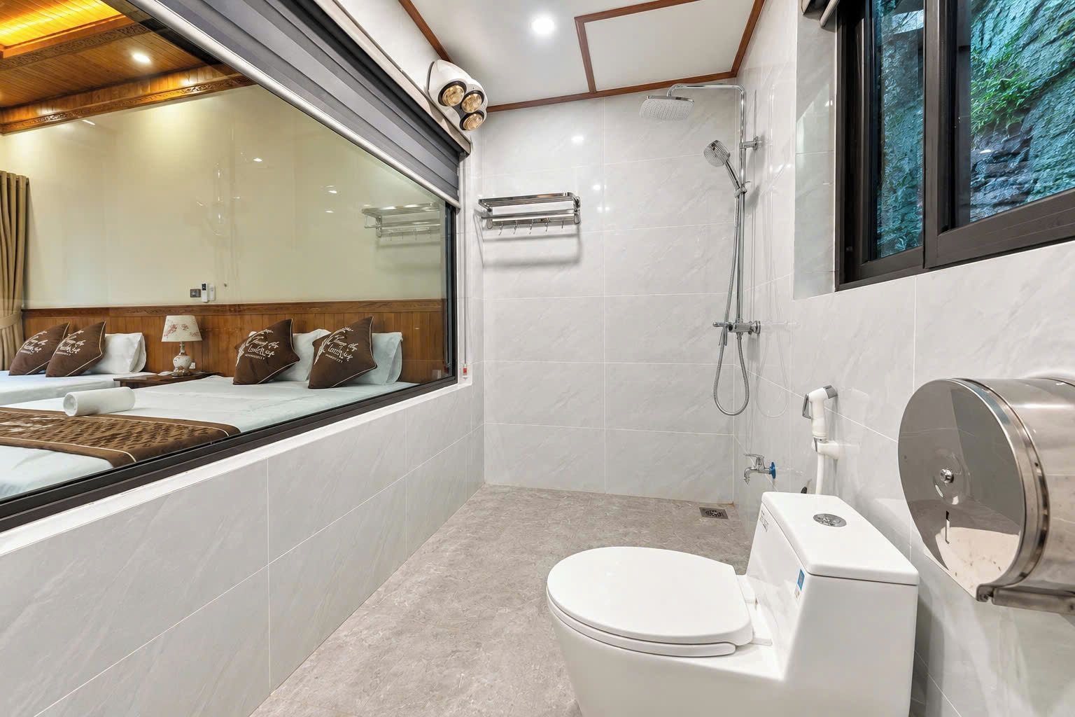 A modern bathroom with a shower, toilet, and a large window.