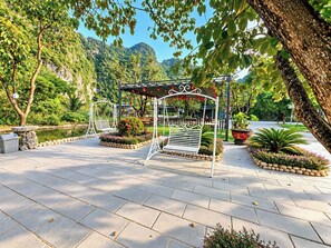 A garden with a white metal gazebo, benches, and a pond. - Trang An Lucky Homestay (Tây Hoa Lư)