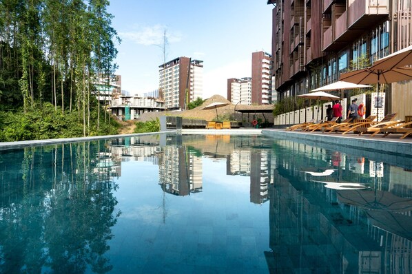 A swimming pool with clear water, surrounded by greenery and modern buildings. - Qubika Boutique Hotel Nusantara (Sepaku)