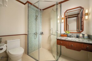 A bathroom with a glass-enclosed shower, a toilet, a sink with a marble countertop, and a mirror with a wooden frame. - Amina Lantana Hoi An Hotel and Spa (Da Nang Municipality)