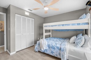 Ein Schlafzimmer mit Etagenbett, Deckenventilator und weißen, verstellbaren Schränken.