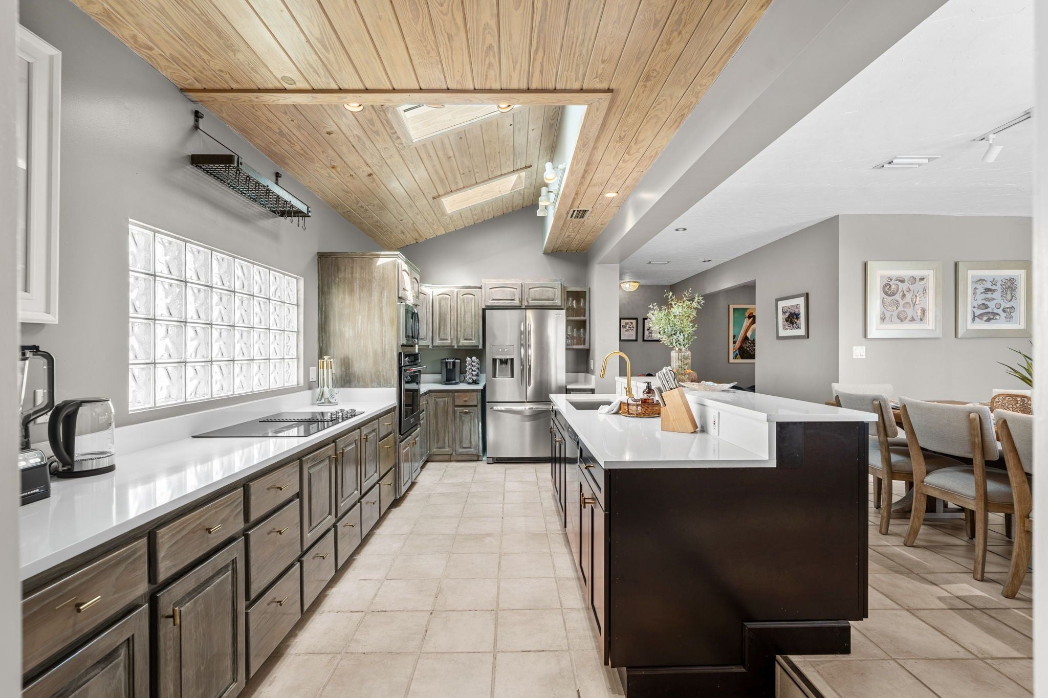 A modern kitchen with a central island, stainless steel appliances, and a wooden ceiling.
