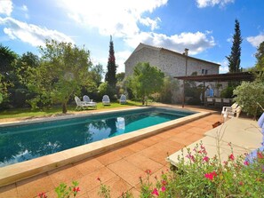 Ein Swimmingpool mit Liegestühlen und einer Pergola in einem Garten.