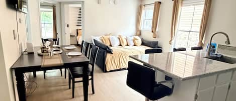 A modern kitchen with a dining area, a bar stool, and a large island.