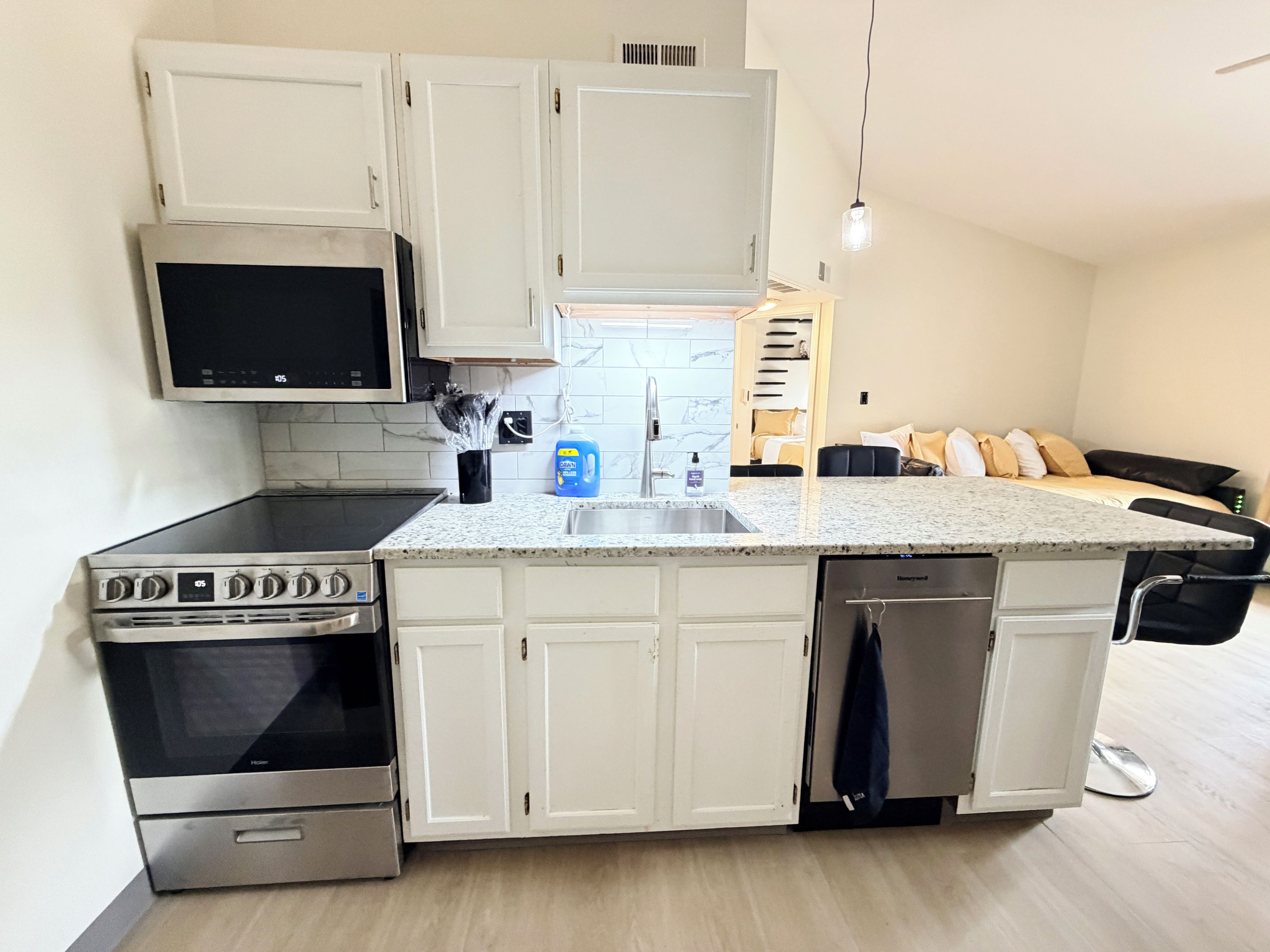 A compact kitchen with white cabinets, a microwave, an oven, and a dishwasher.