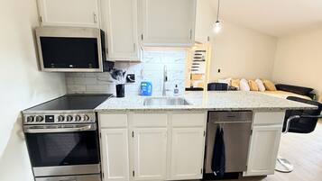 A compact kitchen with white cabinets, a microwave, an oven, and a dishwasher.