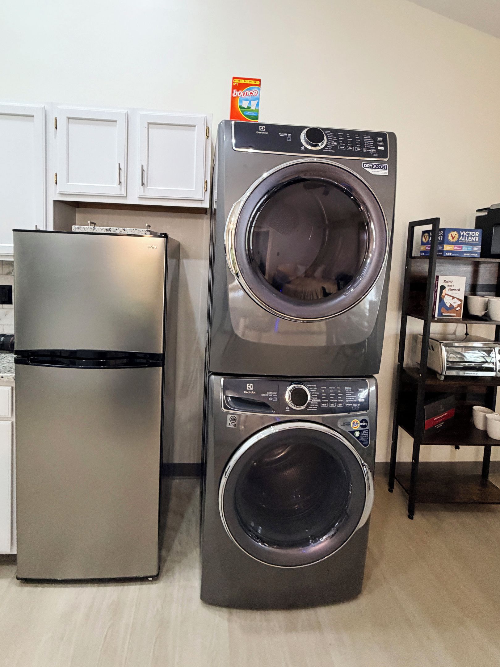 Unit 6 Kitchen showing fridge, in unit washer and dryer, and bookshelf with Keurig, k-cups, toaster, and tea.