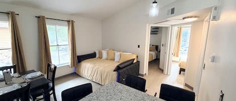 A compact hotel room with a bed, a dining table, and a kitchenette.