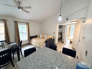 Ein kleines Hotelzimmer mit Bett, Esstisch und einer Küchenzeile.