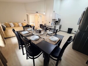 A modern apartment with a dining area, kitchenette, and a living room with a sofa.