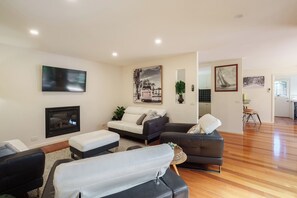 Una sala moderna con una televisión de pantalla plana, una chimenea y un conjunto de sofás.