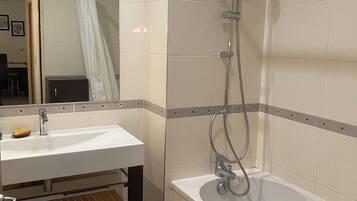 A bathroom with a sink, mirror, shower, and a towel rack.