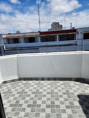 A rooftop terrace with a tiled floor, a metal railing, and a view of buildings in the background. - Modern apartment in central Casablanca (Casablanca)