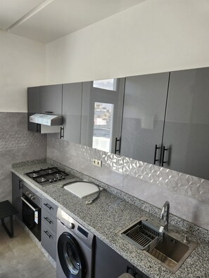 A modern kitchen with a granite countertop, stainless steel appliances, and a built-in washing machine. - Modern apartment in central Casablanca (Casablanca)