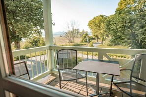 A covered outdoor seating area with a table and chairs, overlooking a landscape with trees and a road. - in the Seedorf holiday park (Neuensien- Sellin)